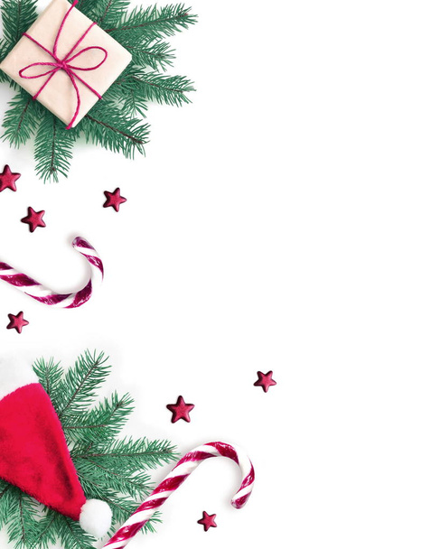 Χριστουγεννιάτικη σύνθεση. Δώρο, έλατο, χριστουγεννιάτικο καπέλο και γλυκό δεκανίκι σε λευκό φόντο. Χριστούγεννα, χειμώνας, Πρωτοχρονιά. Επίπεδη όψη, κορυφή θέα. - Φωτογραφία, εικόνα
