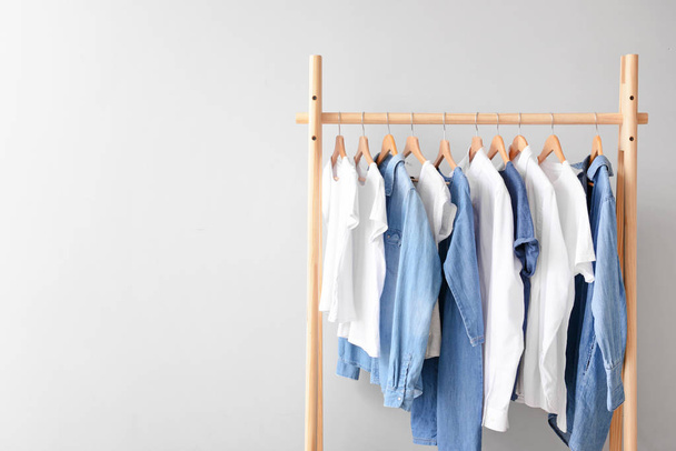 Rack with hanging clothes on light background - Photo, Image
