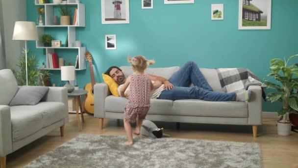 Two little daughters wake dad who sleeps on a sofa - Filmagem, Vídeo