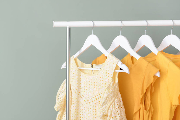 Rack με κρεμασμένα ρούχα στο φόντο χρώμα - Φωτογραφία, εικόνα