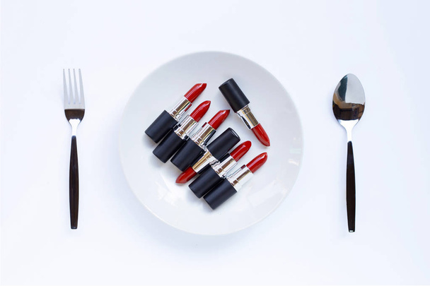 Rouge à lèvres sur plat blanc avec fourchette et cuillère sur blanc
  - Photo, image