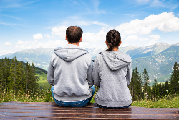 Couple Sitting On Bench Enjoying Panoramic Mountain View - Foto, afbeelding