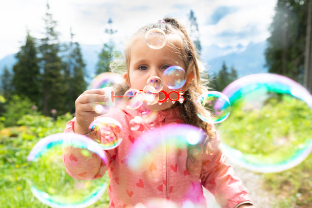 Chica soplando burbujas en un día soleado en el parque
 - Foto, imagen