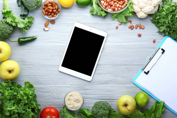 Modern tablet computer with fresh products on wooden background - Photo, Image