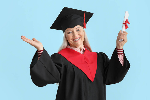 Happy mature woman in bachelor robe on light background - Photo, Image
