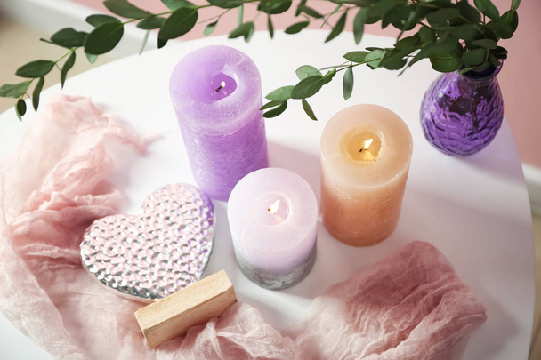 Красивые горящие свечи с эвкалиптом на столе
 - Фото, изображение