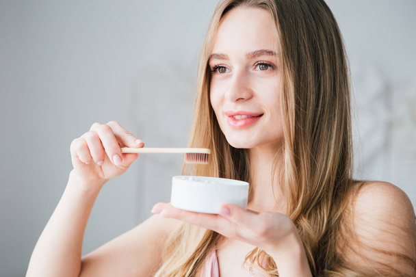 Girl holding a useful bamboo toothbrush and a jar of tooth powder - Photo, Image