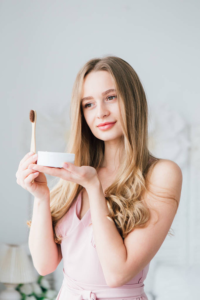 Girl holding a useful bamboo toothbrush and a jar of tooth powder - Foto, Imagem
