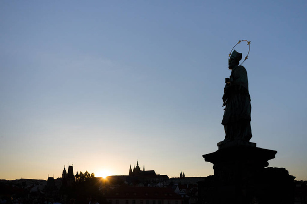 Silhouette of St. John of Nepomuk's Statue on Charles Bridge in Prague with St. Vitus Cathedral in background at sunset. - Foto, immagini