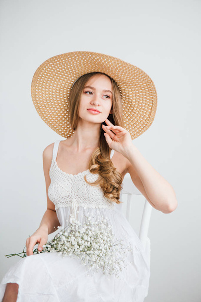 Girl with long hair and hat posing with a bouquet of white flowers - Zdjęcie, obraz