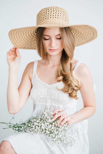 Girl with long hair and hat posing with a bouquet of white flowers - Fotó, kép