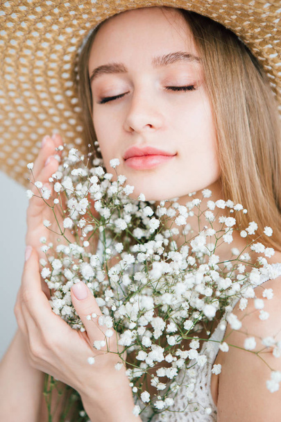 Girl with long hair and hat posing with a bouquet of white flowers - Foto, afbeelding