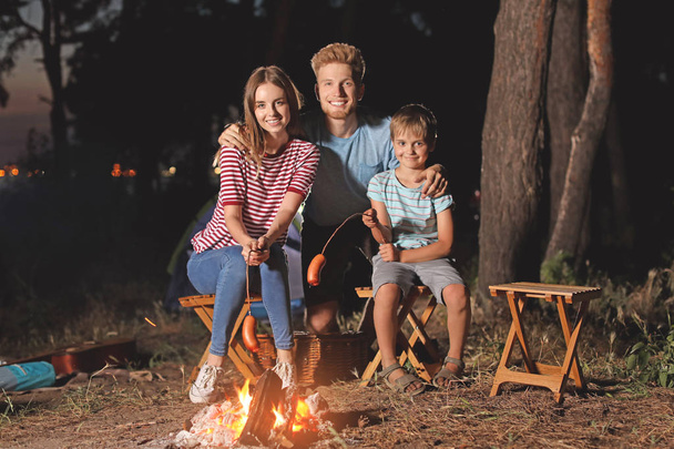 Familie grillt abends Würstchen am Lagerfeuer - Foto, Bild