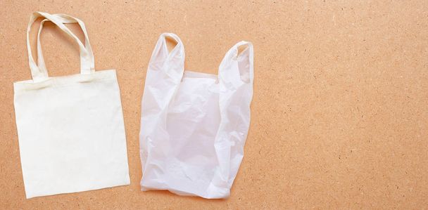 Biała torba na tkaniny z białą plastikową torbą na tle sklejki. - Zdjęcie, obraz