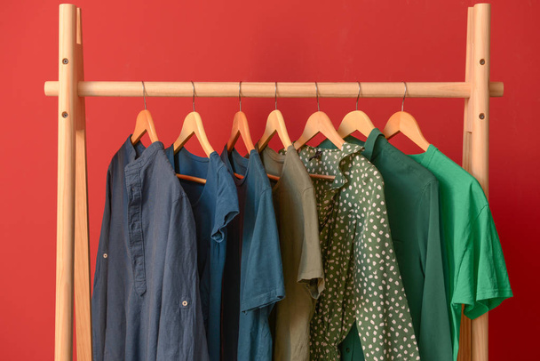 Rack with hanging clothes on color background - 写真・画像