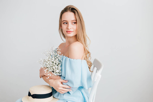 Girl with long hair and hat posing with a bouquet of white flowers - Фото, изображение
