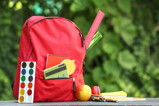 Школьный рюкзак с канцелярскими принадлежностями на улице - Фото, изображение
