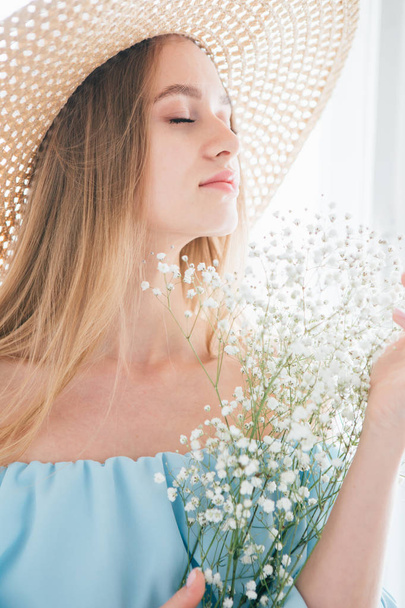Girl with long hair and hat posing with a bouquet of white flowers - Foto, afbeelding