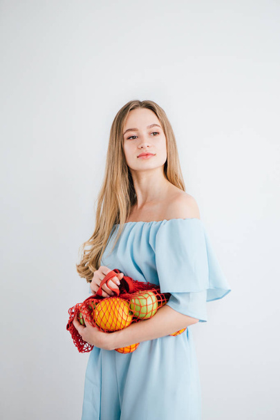 Young beautiful girl with fresh fruit in a string bag - Φωτογραφία, εικόνα