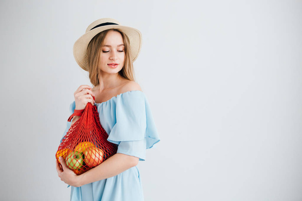 Young beautiful girl with fresh fruit in a string bag - Foto, Imagem