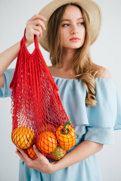 Young beautiful girl with fresh fruit in a string bag - Foto, imagen