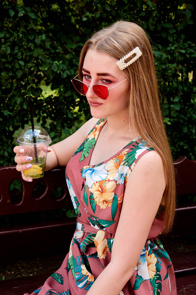 Щаслива радісна молода жінка з кольоровими бавовняними цукерками п'є свіжий коктейль мохіто
. - Фото, зображення
