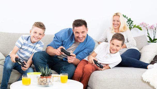 テレビでビデオゲームをプレイする幸せな若い家族. - 写真・画像