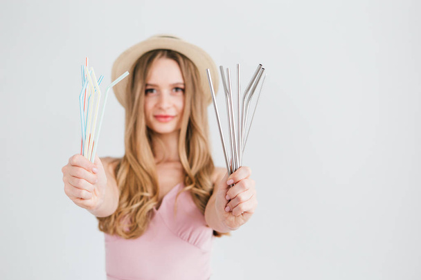 Girl compares useful reusable metal tubes for cocktails with harmful plastic - 写真・画像