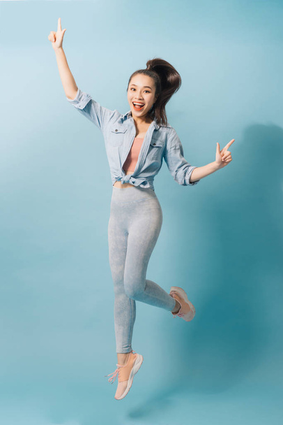 Portrait of playful crazy girl jumping in the air looking at camera enjoying weekend having perfect mood on light blue background - Фото, зображення