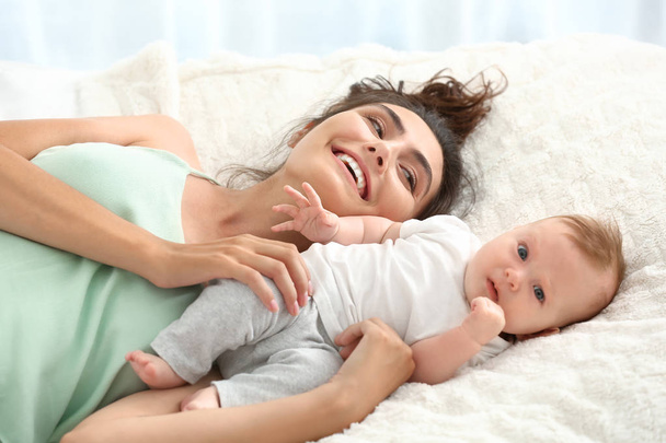 Счастливая мама с милым малышом, лежащим на кровати
 - Фото, изображение