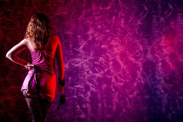 Meisje in BDSM met handboeien en zweep, vrije ruimte voor uw tekst. - Foto, afbeelding