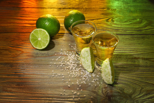 Tomas de tequila sabroso con lima y sal en la mesa de madera
 - Foto, Imagen