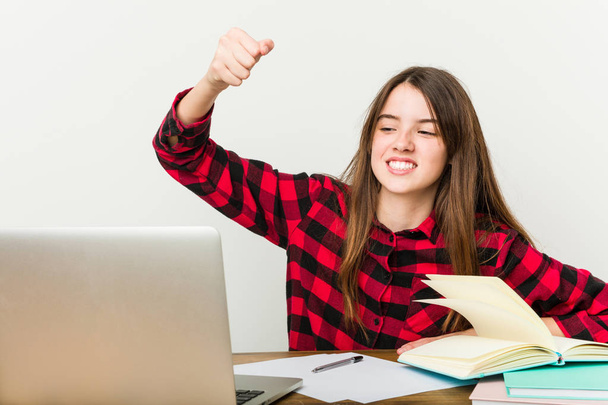 Young teenager going back to her routine doing homeworks showing fist to camera, aggressive facial expression. - Photo, Image