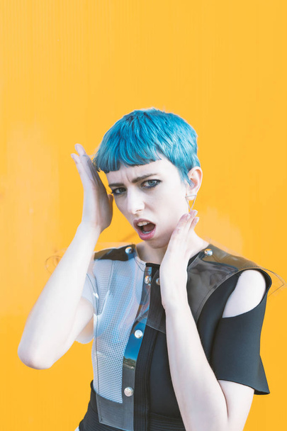 giovane donna in abito futuristico alla moda sul marciapiede contro parete gialla brillante
 - Foto, immagini