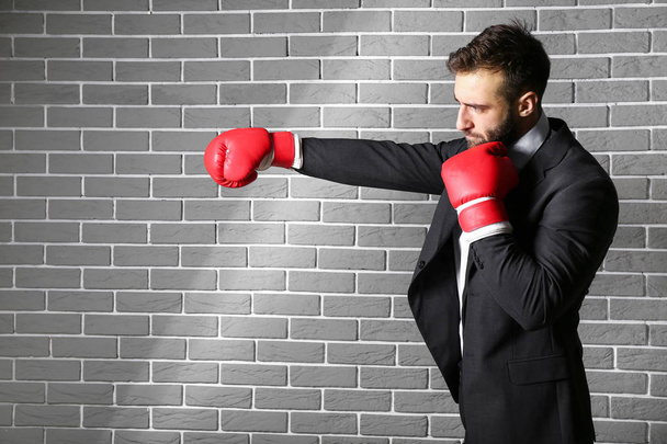 Businessman in boxing gloves against brick wall - Foto, afbeelding