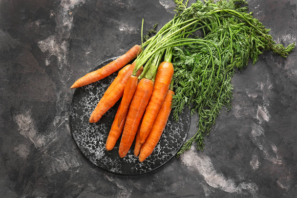 leckere frische Karotte mit Brett auf dunklem Hintergrund - Foto, Bild