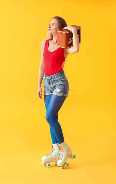 ローラースケートと色の背景に対するレトロなラジオ受信機で美しい若い女性 - 写真・画像