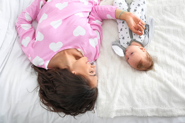 Happy mother with cute little baby lying on bed, top view - Foto, Imagem