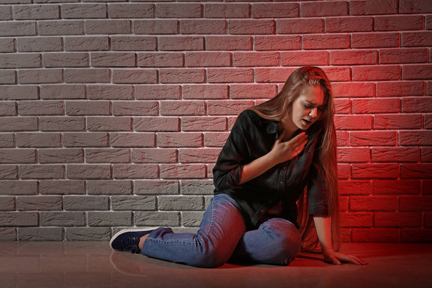 Γυναίκα που έχει κρίση πανικού ενώ κάθεστε κοντά σε τοίχο από τούβλα - Φωτογραφία, εικόνα