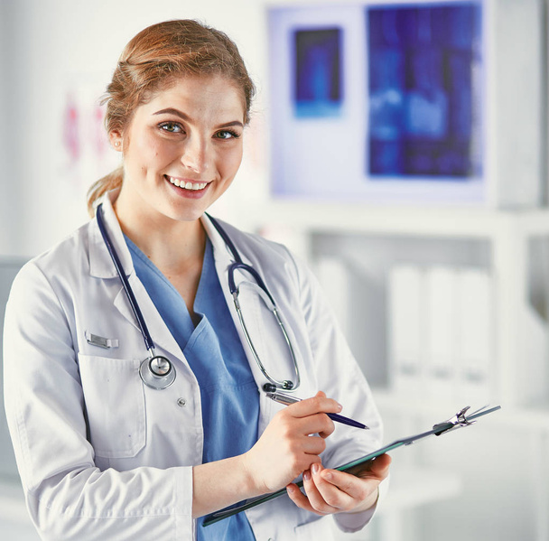 Jovem médico está de pé com placa com prancheta de sorriso
 - Foto, Imagem