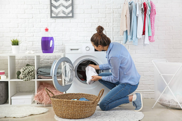Beautiful young woman doing laundry at home - Fotoğraf, Görsel