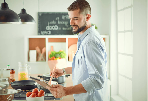 Cuoco sorridente e fiducioso in piedi in una grande cucina - Foto, immagini