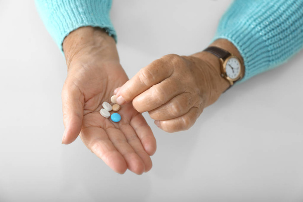 Hands of elderly woman with pills on white background - Photo, Image