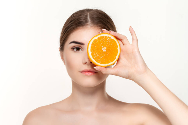 Close-up portrait of a happy beautiful young girl holding half of oranges close to face isolated over white background. - Φωτογραφία, εικόνα