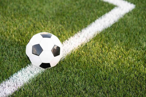 Традиційний чорно-білий м'яч на зеленій траві футбольного стадіону
 - Фото, зображення