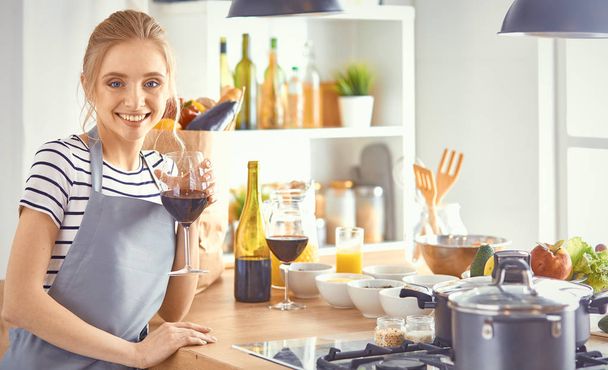Belle femme dans la cuisine boit du vin rouge
 - Photo, image