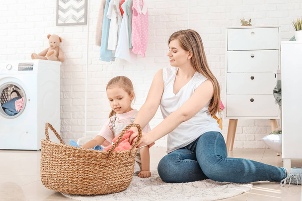 Woman and her little daughter doing laundry at home - Photo, Image
