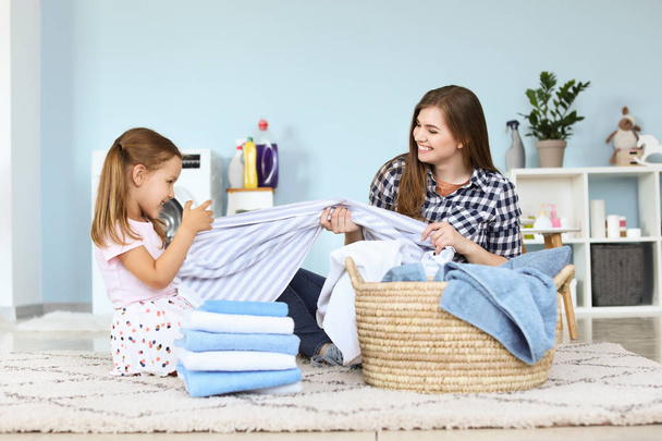 Nainen ja hänen pieni tyttärensä pyykkäämässä kotona
 - Valokuva, kuva
