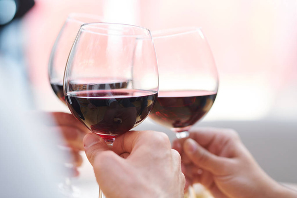 Tre bicchieri da vino con cabernet rosso tenuti da brindare amici godendo festa e festeggiando la festa
 - Foto, immagini