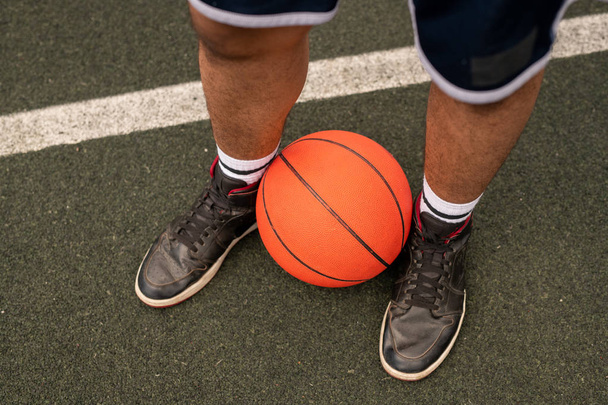 Balle par les jambes du jeune joueur de basket professionnel debout sur l'aire de jeux par la ligne blanche
 - Photo, image